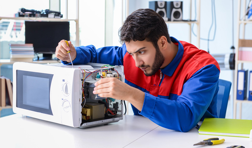 Young repairman fixing and repairing microwave oven